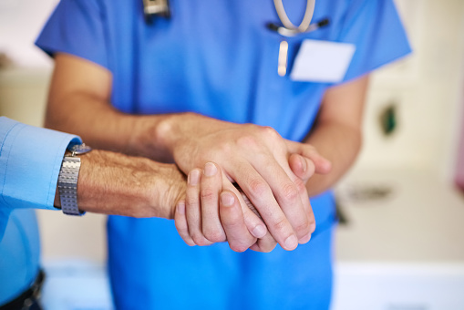 Shot of an unidentifiable young doctor holding his senior patient's hand in support