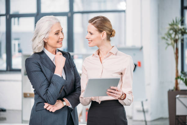 istock Two smiling businesswomen using digital tablet and talking in office 693600774
