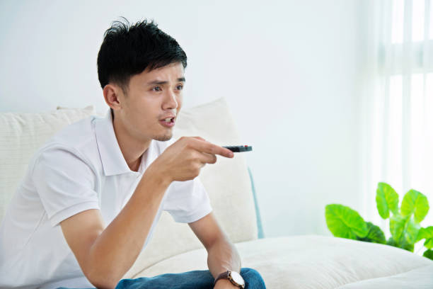 istock Young asian man watching television on sofa 693600812