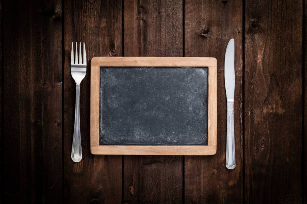 istock Chalkboard with fork and knife on wooden table 693610730