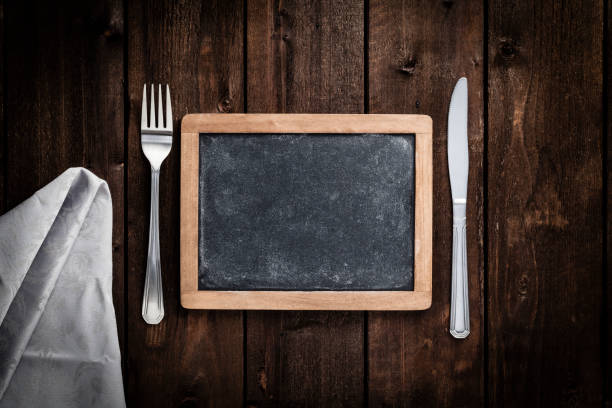 istock Chalkboard with fork and knife on wooden table 693610752