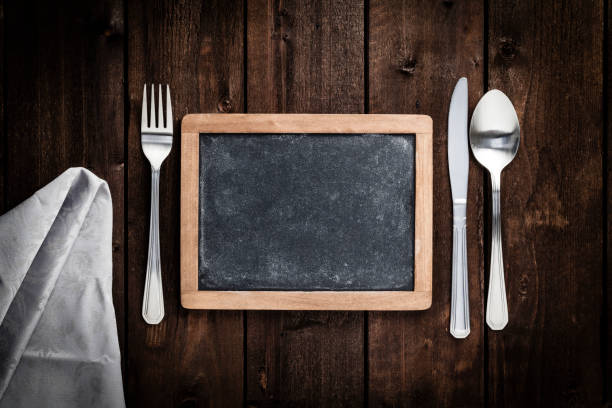 istock Chalkboard with fork and knife on wooden table 693610808