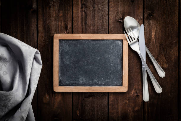 istock Chalkboard with fork and knife on wooden table 693610936