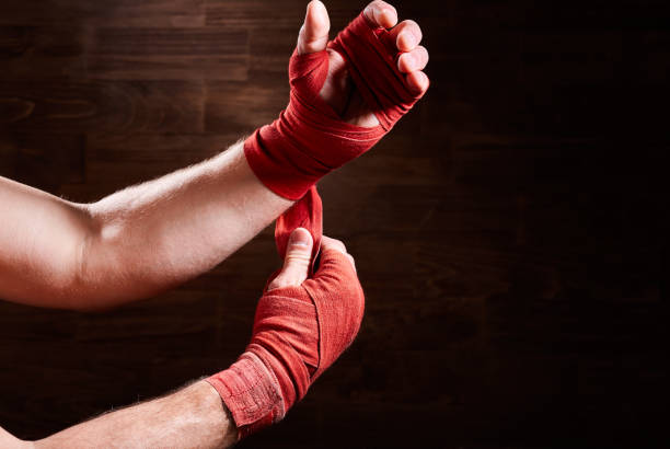 istock Boxer putting bandage around wrists and hands against brown wall. 693616686