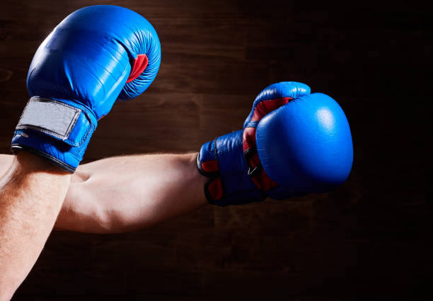 istock Blue and red boxing gloves on hands on brown background. 693616744