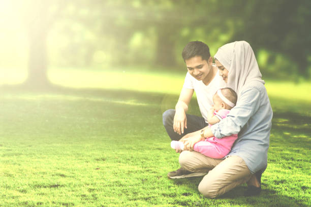 istock Muslim parents squatting with baby in meadow 693620766