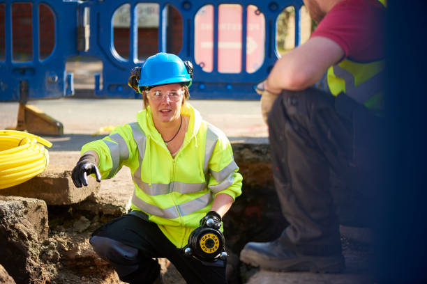 civil engineer a female gas engineer holds a new gas valve as she and a colleague prepare to replace the old pipework in a residential uk street . laying underground pipes stock pictures, royalty-free photos & images