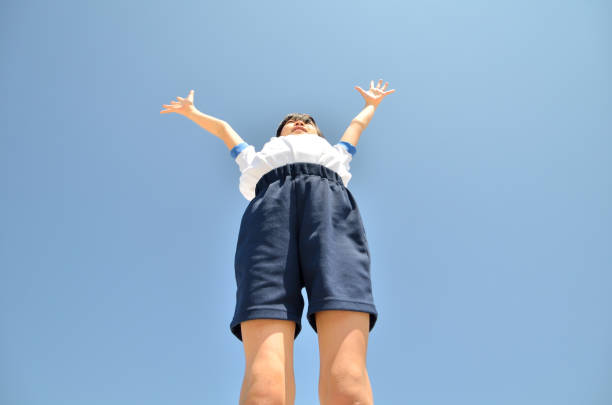 Girl looking up at blue sky (gym clothes) Girl looking up in blue sky (gym clothes) artistic gymnastics stock pictures, royalty-free photos & images