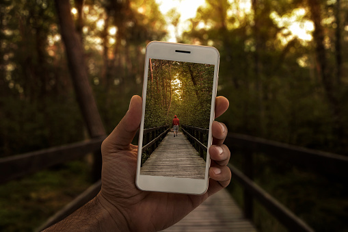 Travel concept, close up of a male hand photographing person in the forest