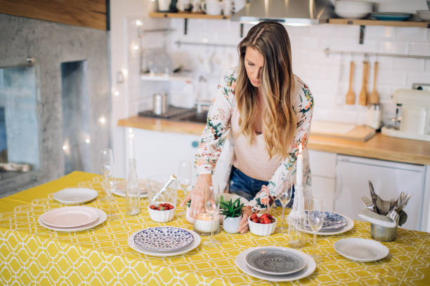 She likes to entertain friends at home Woman arranging table for home dinner with friend or family. place setting table plate dining table stock pictures, royalty-free photos & images