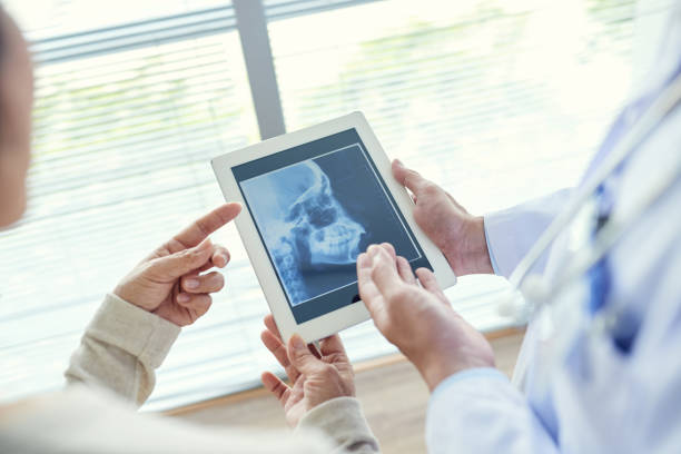 istock Dentist Showing X-ray to Patient 693635024