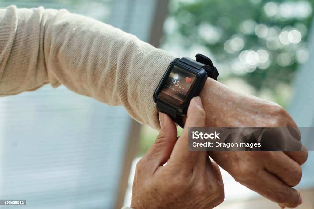 Wrinkled Hand with Fitness Tracker Close-up shot of wrinkled female hand with modern fitness tracker, blurred background Fitness Tracker Stock Photo