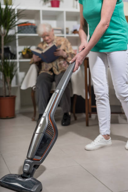 istock Home helper vacuuming for an old woman 693635778