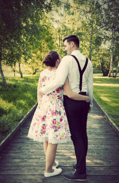 istock Young couple embrace while standing on wooden path 693644018