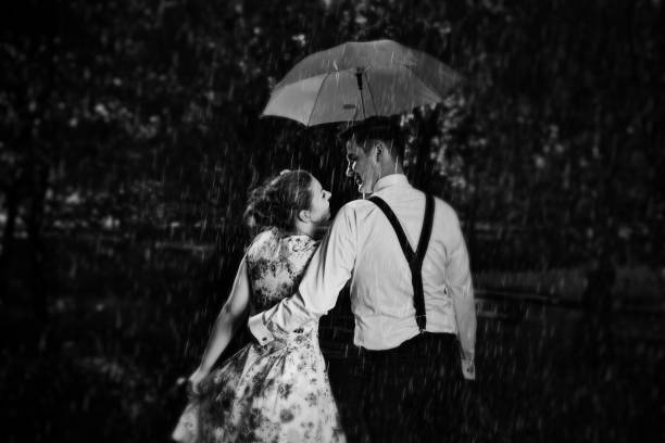 Young romantic couple in love flirting in rain. Black and white Young romantic couple in love flirting in rain, man holding umbrella. Dating, romance, black and white umbrella photos stock pictures, royalty-free photos & images