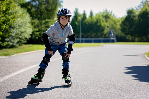 Cute little child, boy, riding on a rollerblades in the park, springtime