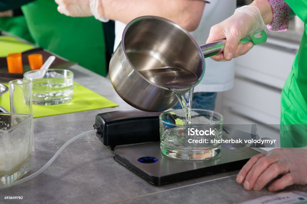 pouring water from a pan into a glass The process of pouring water from a pan into a glass on a culinary scales Cooking Stock Photo