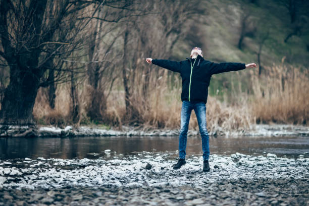 istock Happy jumping man in beautiful river landscape 693665796