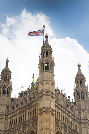 Union Jack fluttering above the highly decorative architecture of the Palace of Westminster