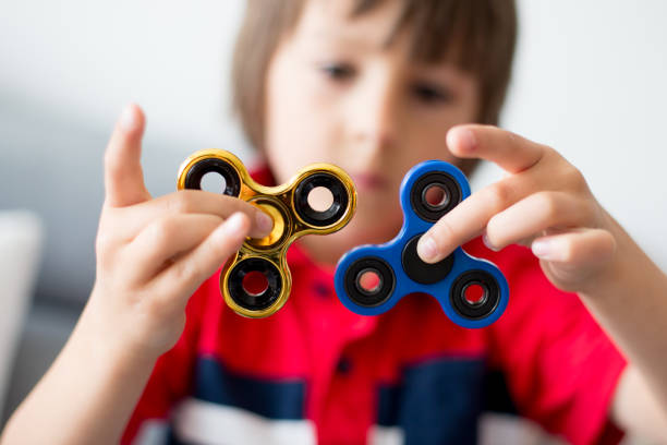 klein kind, jongen, spelen met twee fidget spinner speelgoed - handspinner stockfoto's en -beelden