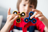 Little child, boy, playing with two fidget spinner toys