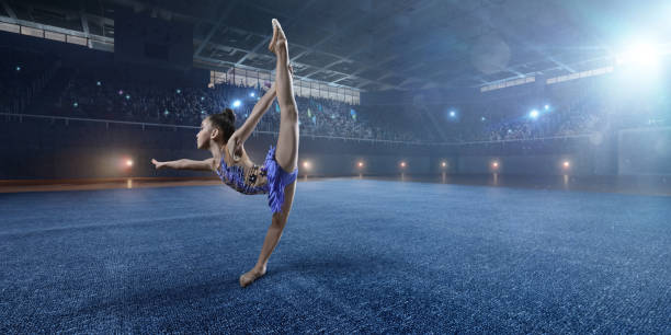 istock A small gymnast girl makes performance on a large professional stage 693674610