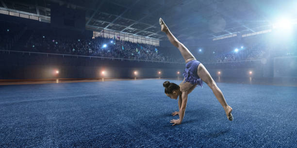 istock A small gymnast girl makes performance on a large professional stage 693674618