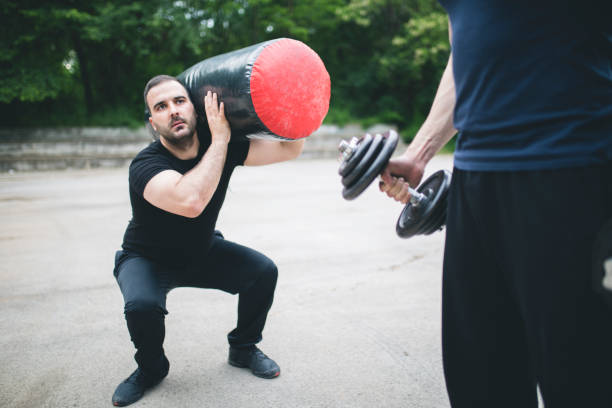 istock Two Man Performing Bag Squat Exercise Outdoor 693682962