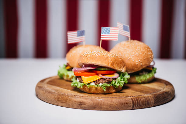 istock Three cheeseburgers with little american flags on wooden board 693697250