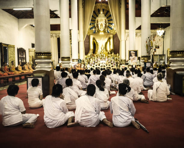 Group of people attending Buddhist mass in Phra Singh temple in Chiang Mai Thailand