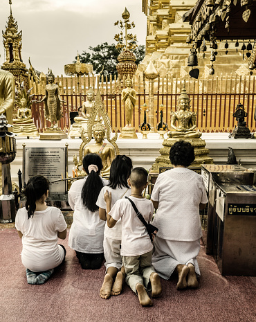 People praying inside Wat Phra That Doi Suthep Chiang Mai Thailand. This temple in the outskirts of the city located on the top of a mountain that overlooks the city is a Theravadada wat was founded in 1383. the Gautama Buddha's shoulder bone is supposed to be housed here as a relic.