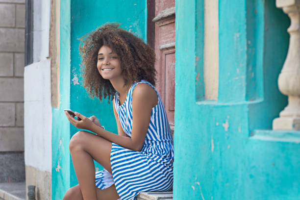 istock Woman using mobile phone while sitting at entrance 693697484