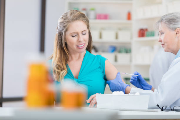 istock Young woman grimaces while receiving flu shot 693699552