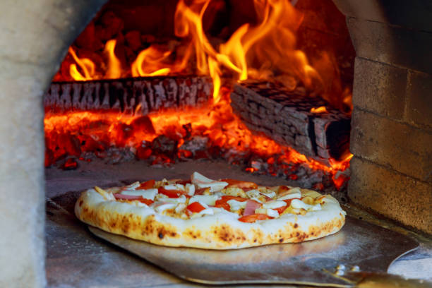 istock Close up pizza in firewood oven with flame behind 693722322