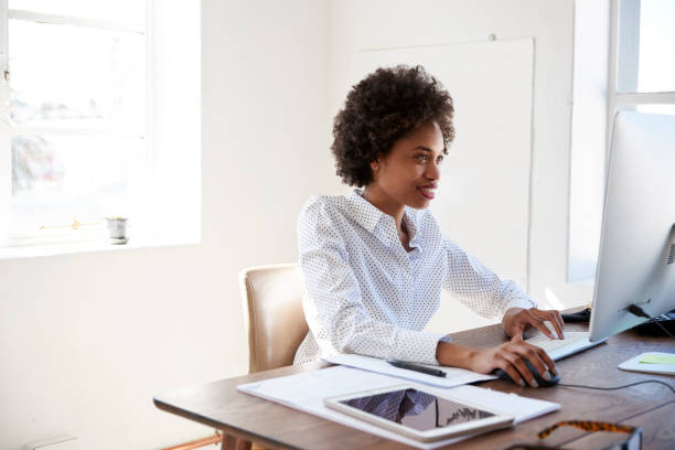 istock Young black woman working at computer in an office, close up 693722576