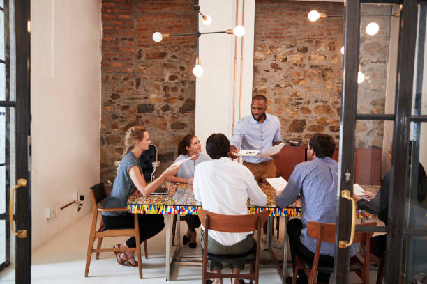 istock Young black man handing out paperwork at a team meeting 693725988
