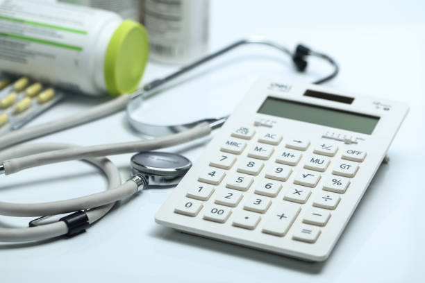 istock calculator, stethoscope and medicine bottles on white background 693736488