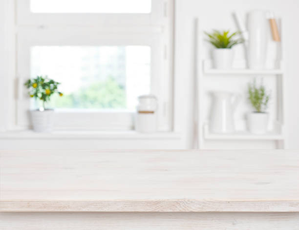 istock Empty bleached wooden table and kitchen window shelves blurred background 693744752