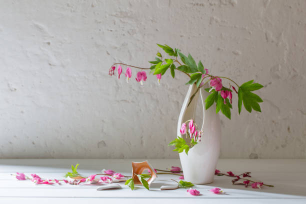 istock pink flowers in  broken vase on old white background 693771420