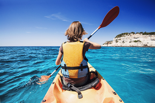 Young girl kayaking in a sea. Active lifestyle and travel concept