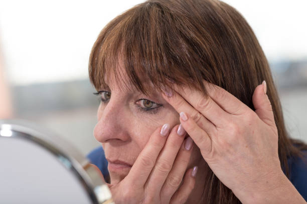 istock Mature woman looking at her eye wrinkles 693777878