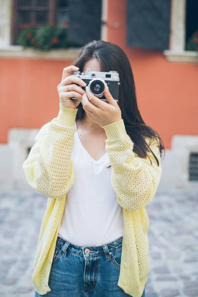 istock young pretty woman taking picture with old camera 693781004