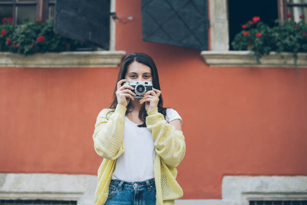 istock young pretty woman taking picture with old camera 693784396