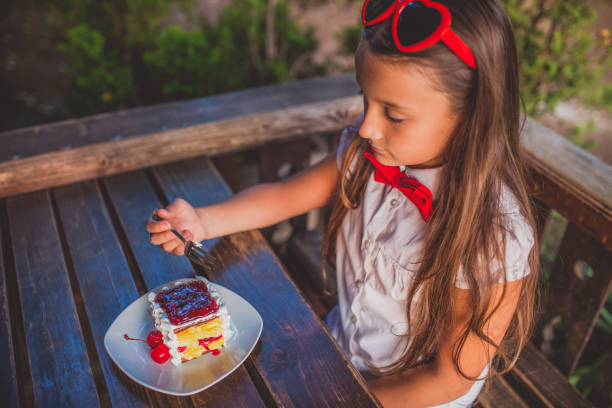 Little girl eating cake and having fun at the park