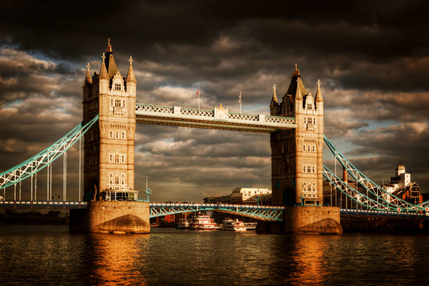 Tower Bridge in London, the UK. Dramatic stormy and rainy clouds with sunset sun shining. One of the symbol of England, Great Britain