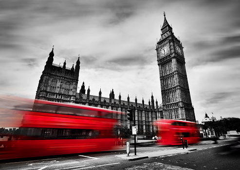 London, the UK. Red buses in motion and Big Ben, the Palace of Westminster. The icons of England in black and white with red colour.