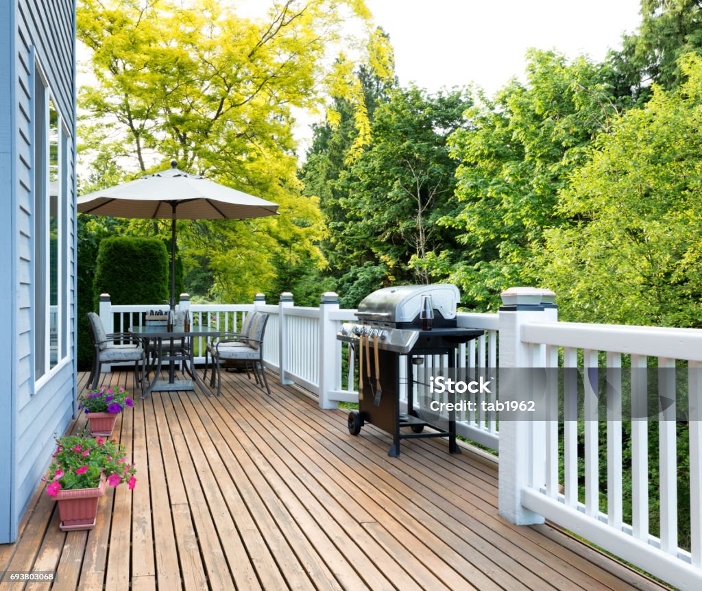 Home deck and patio with outdoor furniture and BBQ cooker with bottled beer Clean outdoor cedar wooden deck and patio of home with BBQ cooker and bottled beer Deck Stock Photo
