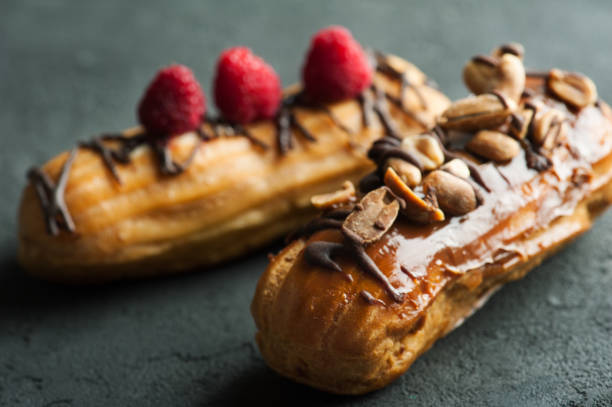istock Eclairs with peanuts, chocolate icing and raspberries 693803846