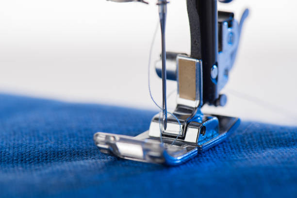 istock Close-up view of working sewing machine sewing blue fabric 693804110