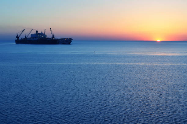 The ship that is laying a gas pipe on the sea bottom against the sunset